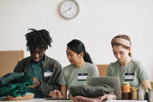 group of three diverse volunteers looking at phone and laptop